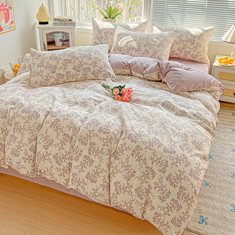 A floral printed bedding set featuring soft pink and beige tones on a bed with white blinds.