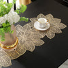 Gold leaf patterned placemat with a white teacup and greenery on a black table.
