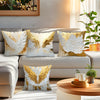 Decorative throw pillow covers featuring golden and white wing patterns on a neutral sofa.