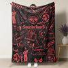 A black blanket featuring a retro punk print design with skulls and text.