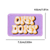 A purple iron-on embroidery patch featuring the text OKEY DOKEY in orange stitching.