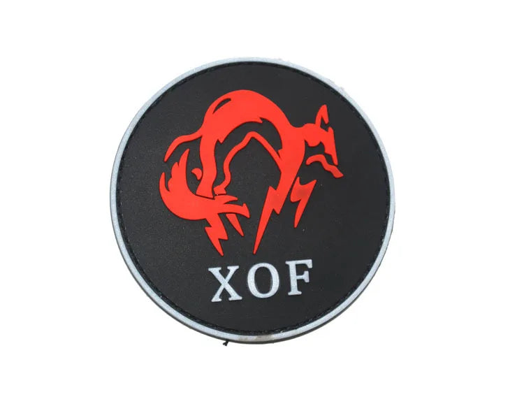 A round black patch with a red silhouette of a fox and the letters XOF embroidered on it.