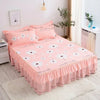 Pink double layer printed bed skirt with white floral pattern and pink pillows on a bed.