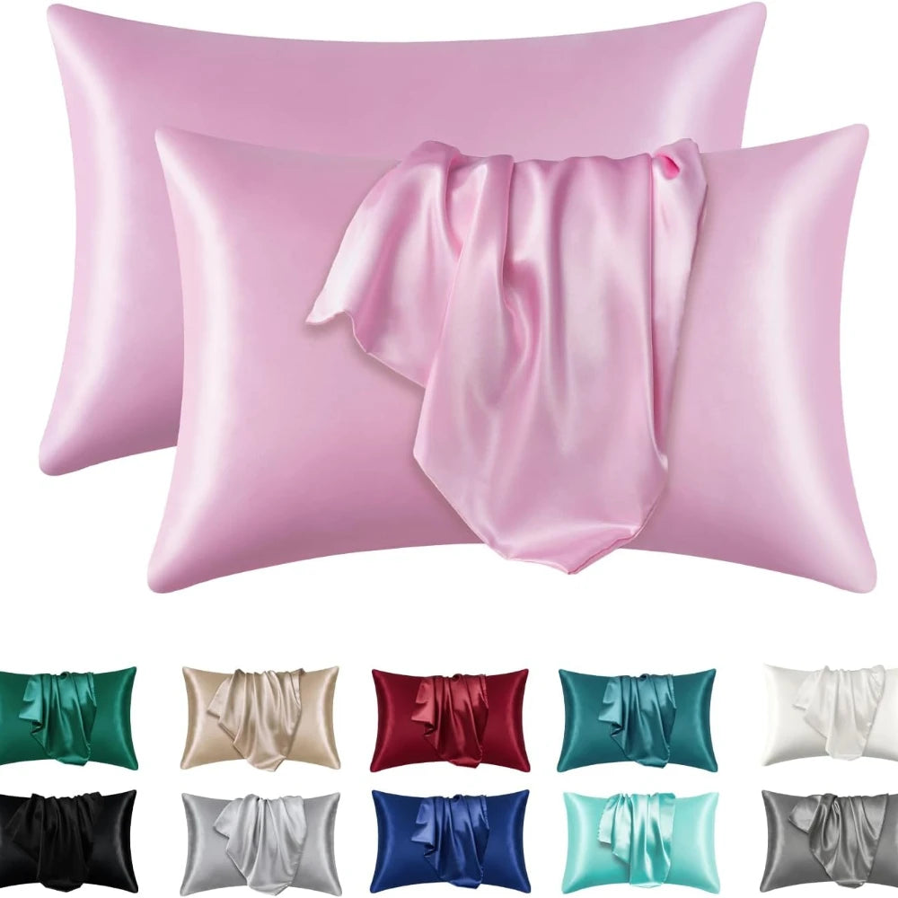A collection of silky satin pillowcases in various shades of pink, including light pink, medium pink, and rose.