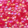 A close-up of small, translucent pink and red acrylic heart beads for jewelry making.
