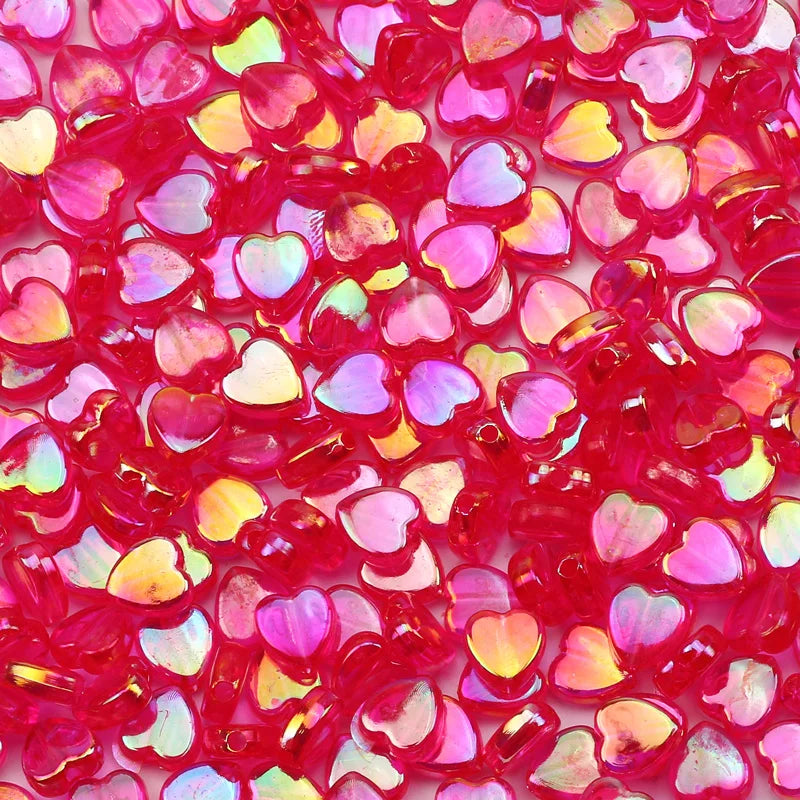 A close-up of small, translucent pink and red acrylic heart beads for jewelry making.