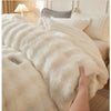 A close-up of a fluffy cream colored rabbit quilt comforter being held, showing its soft texture and plush appearance.