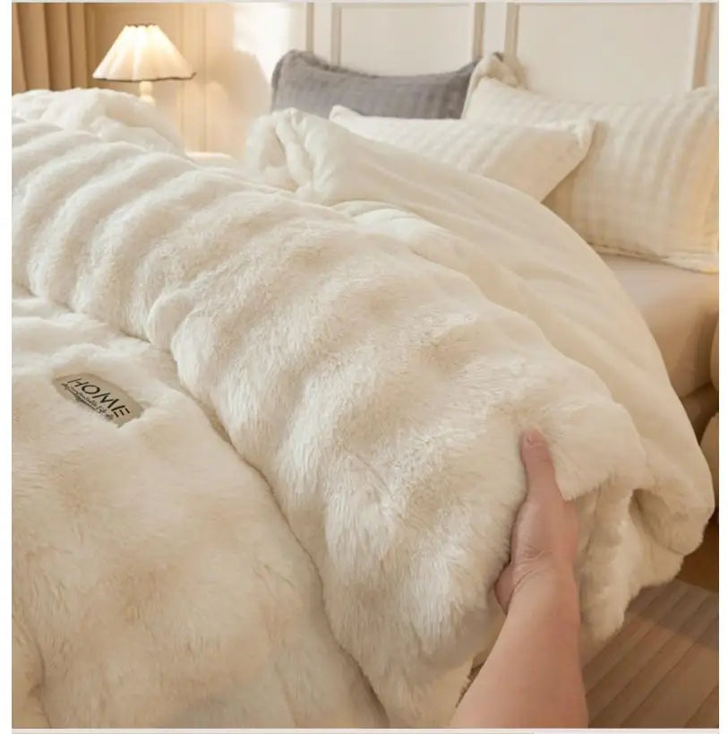 A close-up of a fluffy cream colored rabbit quilt comforter being held, showing its soft texture and plush appearance.