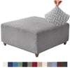 Gray stretch jacquard ottoman cover with a textured pattern and a matching fabric swatch strip.