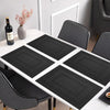A set of six black non-slip heat resistant placemats arranged on a white dining table.