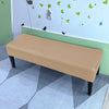 A beige stretch pu leather waterproof bench slipcover placed on a light-colored floor in a room with a white wall and green t