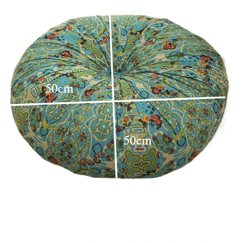 A round cushion covered in blue and green bohemian cotton linen fabric with a white cross dividing the surface.