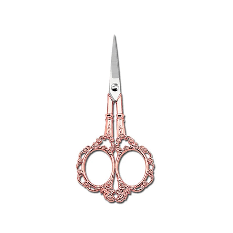 A pair of pink rose gold crafting scissors with a silver blade and ornate handles.