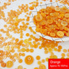A pile of assorted resin sewing buttons in shades of orange and yellow scattered on a white surface.