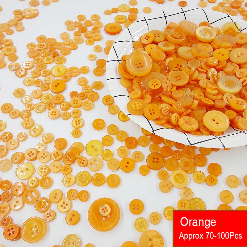 A pile of assorted resin sewing buttons in shades of orange and yellow scattered on a white surface.