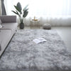 A fluffy gray luxury velvet anti-slip floor mat placed on a light floor with a potted plant and decorative items.