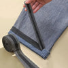 Close-up of black iron-on hem tape being applied to the cuff of a denim pant leg.