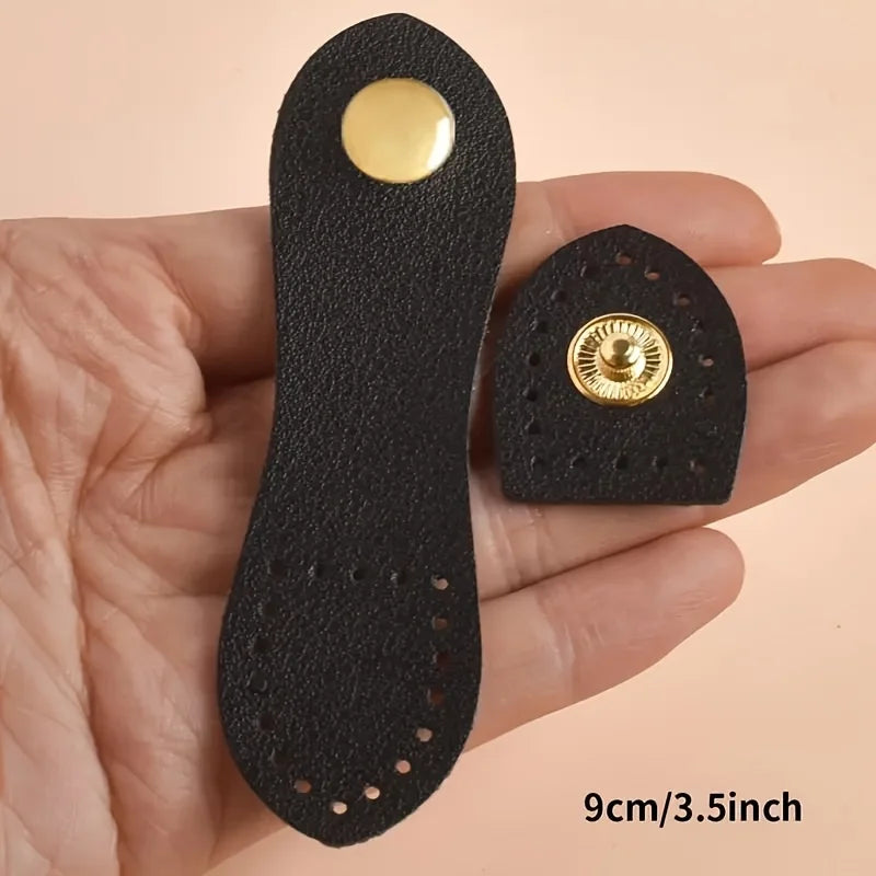A black leather bag buttons set with gold accents is shown in a person's hand.