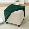 A dark green velvet ottoman slipcover draped over a light beige upholstered furniture piece.