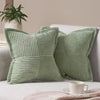 A set of light green striped corduroy lumbar support pillows resting on a white sofa.