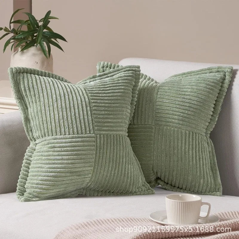 A set of light green striped corduroy lumbar support pillows resting on a white sofa.