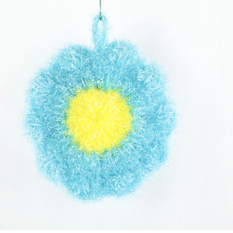 A blue and yellow flower-shaped kitchen dish scrubber sponge with a fluffy texture.