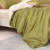 A luxury bamboo duvet cover set in olive green fabric draped over a bed with light beige pillows.