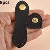 A hand holds a set of eight black leather bag buttons with gold accents.