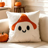 A white throw pillow cover featuring an orange pumpkin design on a light-colored sofa.