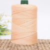 A spool of peach colored 3mm ice rope crochet yarn with a green cap resting on a woven mat.