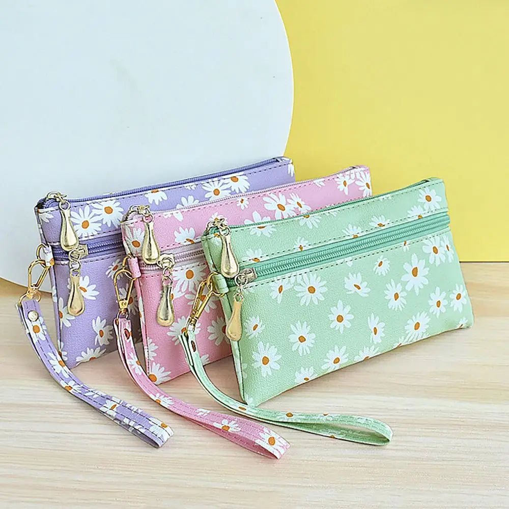 A collection of purple, pink, and green PU leather coin purses with gold hardware and wrist straps displayed on a light woode