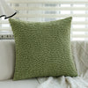 A textured moss green embroidered floral cushion cover resting on a light-colored sofa.