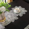 A white porcelain teacup and saucer rest on a decorative white lace placemat on a black table.