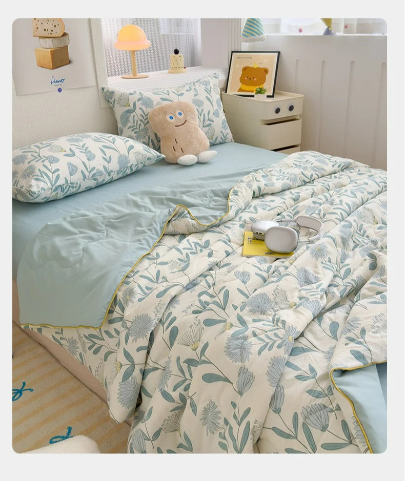 A light blue summer gauze cotton quilt spread on a bed with white and beige decor.