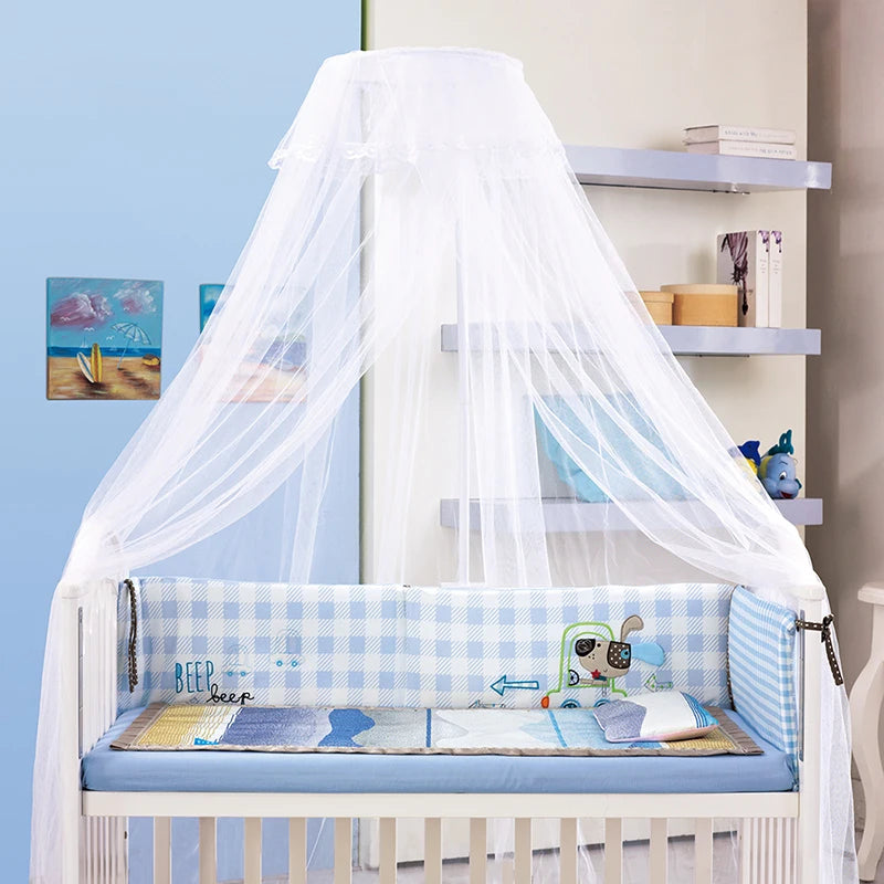 White sheer mosquito net canopy draped over a baby cot with blue and white patterned bedding