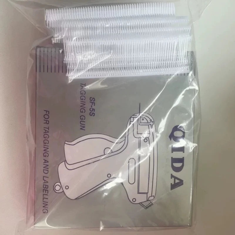 A clear plastic package containing a precision sewing tag gun kit with multiple white tagging needles.