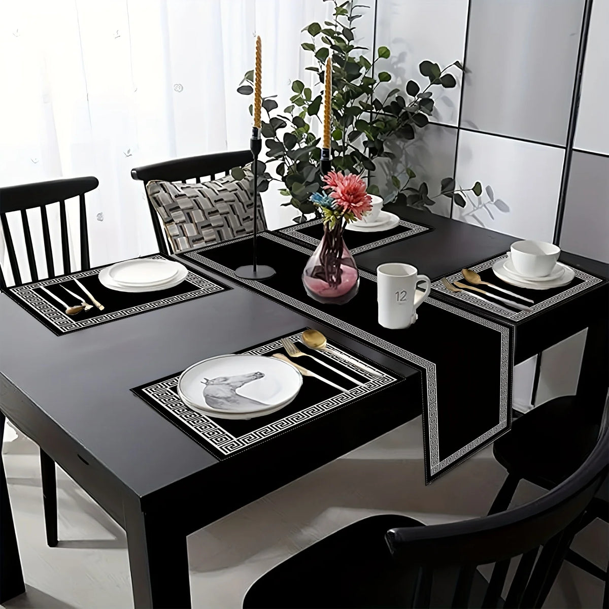 A black dining table set featuring geometric placemats, cutlery, and a table runner with white porcelain dishes.