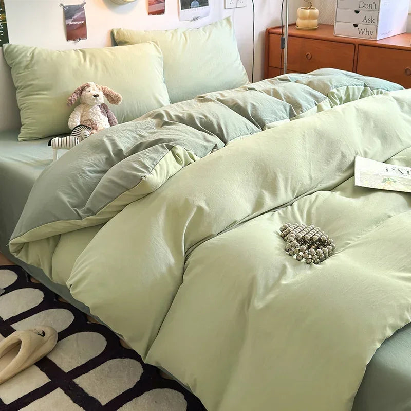 A close-up of a bed with light green quilted bedding and pillows, featuring a small stuffed animal.