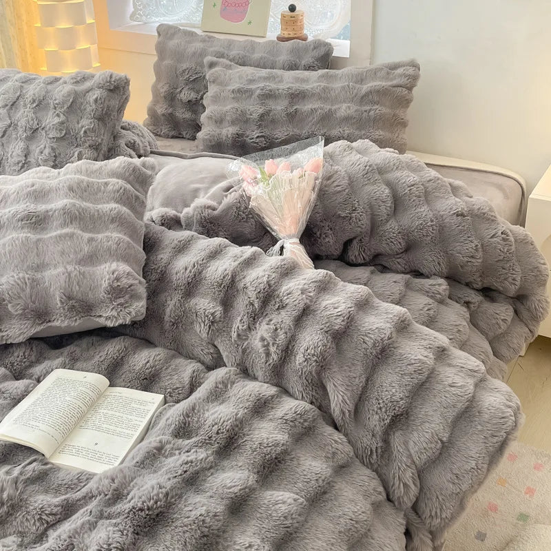 A gray plush rabbit hair bedding set featuring fluffy pillows and a textured blanket.