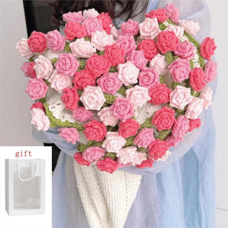 A bouquet of handmade rose crochet flowers in pink and red shades displayed against a light blue fabric.