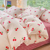 A close-up of a beige bedding set featuring a pattern of red cherries on a white background.