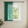 A dark green lace curtain with a wave border hanging in a white window frame.