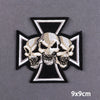 Black and white embroidered cross patch featuring three skulls on a gray background