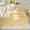 A yellow quilted lightweight cooling summer quilt set displayed on a white bed with pillows and decor.
