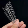 A hand holds a set of precision beading needles for jewelry making, showing the fine metal tools.