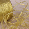 A close-up of gold and silver glitter satin ribbon spilling out, with a large spool visible in the background.