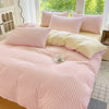 A pink and white checkered duvet cover set displayed on a bed with matching pillows.
