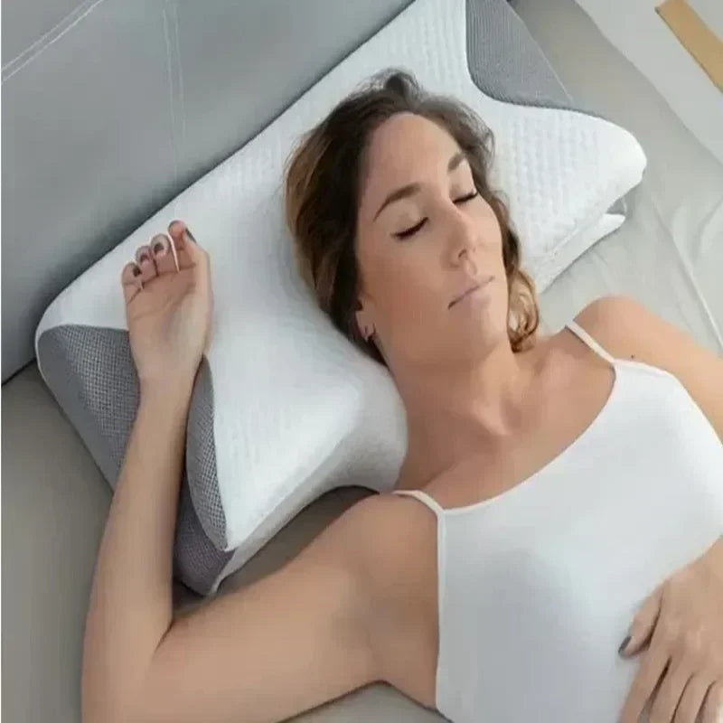 A woman is lying down and resting her head on a white memory foam contour pillow for neck pain relief.