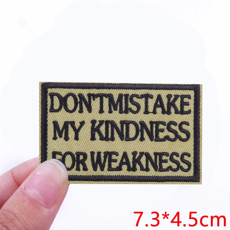 A rectangular black embroidered patch with beige text that reads DON'T MISTAKE MY KINDNESS FOR WEAKNESS