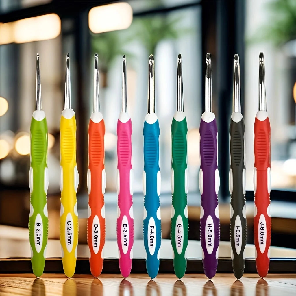 A row of ergonomic felt crochet hooks in various colors and sizes displayed on a wooden surface.